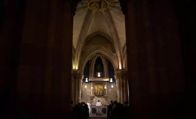 A priest celebrates Mass in the crypt of Antoni Gaudí beneath the Sagrada Familia while crowds of visitors fill the basilica above in Barcelona, Spain, May 15, 2026. (AP Photo/Emilio Morenatti)