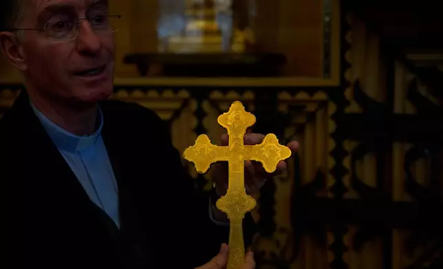 Josep Maria Turull, rector of the Basilica of the Sagrada Familia, holds a cross-shaped relic beside cabinets containing some of the basilica's most precious relics and liturgical vestments in Barcelona, May 15, 2026. (AP Photo/Emilio Morenatti)