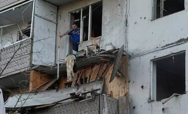 A man clears debris in his apartment building damaged after Russian missile strike that hit in Kyiv, Ukraine, Tuesday, June 2, 2026. (AP Photo/Efrem Lukatsky)