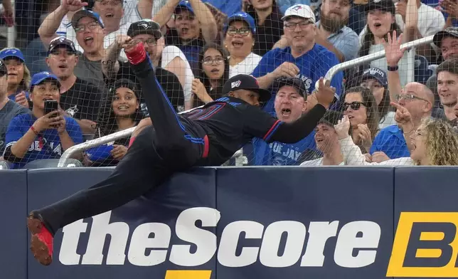 Toronto Blue Jays first baseman Vladimir Guerrero Jr., center, makes a barehanded catch during fifth-inning baseball game action against the Baltimore Orioles in Toronto, Friday, June 5, 2026. (Nathan Denette/The Canadian Press via AP)