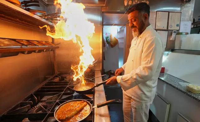 Chef Mohammed Shanoor Ali cooks at a Bangladeshi restaurant in London, Thursday, June 18, 2026. (AP Photo/Kin Cheung)