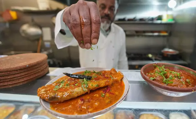 Chef Mohammed Shanoor Ali prepares food at a Bangladeshi restaurant in London, Thursday, June 18, 2026. (AP Photo/Kin Cheung)