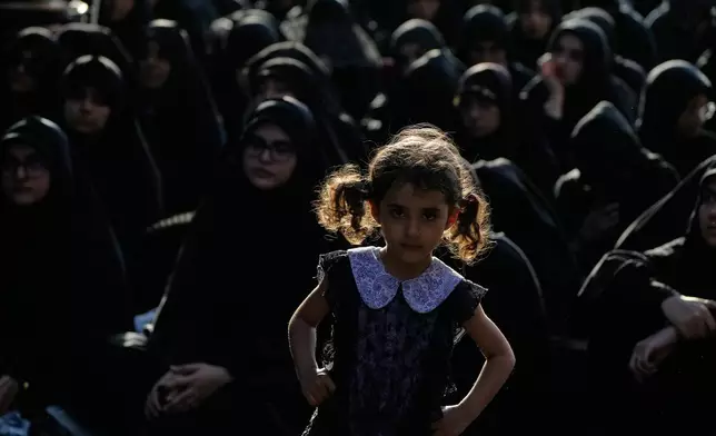 A girl looks on as women sit during a mourning ceremony in Tehran, Iran, Thursday, June 18, 2026, ahead of Ashoura, which honors the 7th-century martyrdom of the Prophet Muhammad's grandson, Hussein, who was killed in a battle in Karbala in present-day Iraq. (AP Photo/Vahid Salemi)