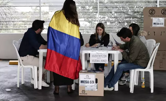 A woman wrapped in a Colombian flag votes during the presidential election in Bogota, Colombia, Sunday, May 31, 2026. (AP Photo/Jose Vargas)