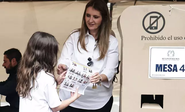 Presidential candidate Paloma Valencia of the Democratic Center party shows her ballot to her daughter during the presidential election in Bogota, Colombia, Sunday, May 31, 2026. (AP Photo/Jose Vargas)