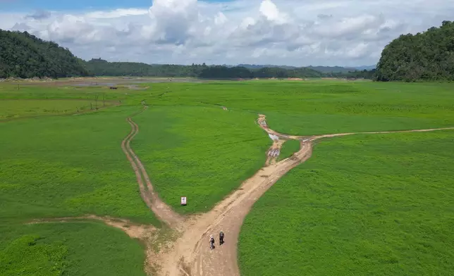 Researchers walk into the empty reservoir where Nithe Station, a depot on World War II's infamous "Death Railway" resurfaced after the reservoir was drained in Sangkhlaburi, Thailand on Friday, May 29, 2026. (AP Photo/Anton L. Delgado)