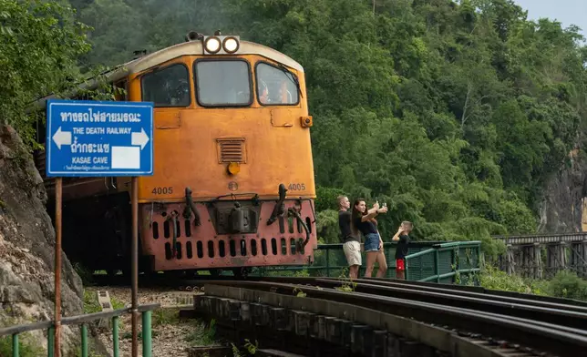 A family of Russian tourists pose for photos as a train approaches Thamkra Sae Station, one of the still active sections of the infamous World War II "Death Railway," in Sai Yok, Thailand, Thursday, May 28, 2026. (AP Photo/Anton L. Delgado)