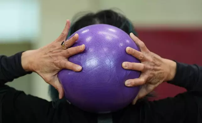 A participant grabs an exercise ball during a class for older adults led by instructor Bengie Santos at the Dale Turner Family YMCA, April 30, 2026, in Shoreline, Wash. (AP Photo/Lindsey Wasson)