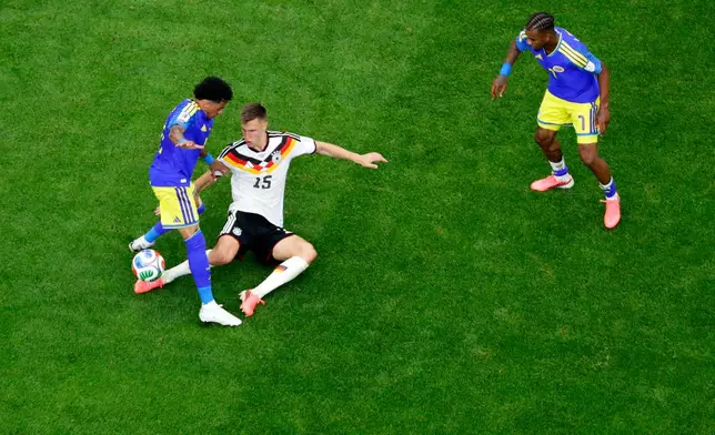 Germany's Nico Schlotterbeck (15) is tackled by Curaçao's Jeremy Antonisse, left, as Curaçao's Juninho Bacuna (7) watches during the World Cup Group E soccer match between Germany and Curacao in Houston, Sunday, June 14, 2026. (AP Photo/Michael Wyke)