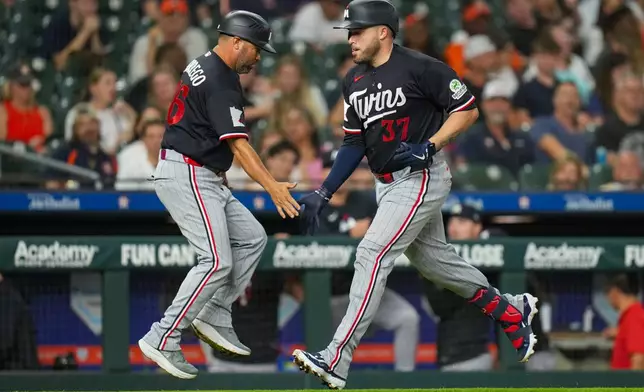 Minnesota Twins' Victor Caratini (37) greets third base coach Ramon Borrego, left, while rounding the bases on his solo home run during the fourth inning of a baseball game in Houston, Monday, June 29, 2026. (AP Photo/Jon Shapley)