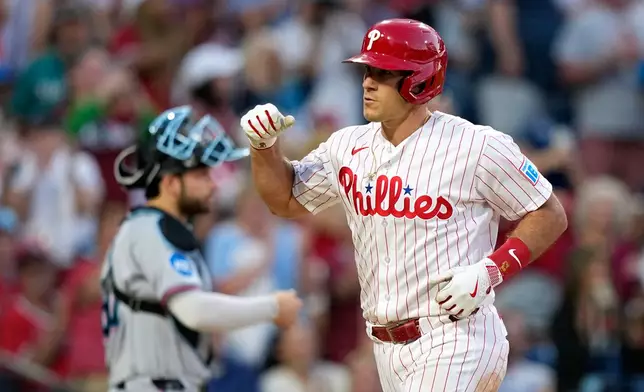 Philadelphia Phillies' J.T. Realmuto, right, reacts after hitting a two-run home run against Miami Marlins pitcher Ryan Gusto during the fifth inning of a baseball game Monday, June 15, 2026, in Philadelphia. (AP Photo/Matt Slocum)