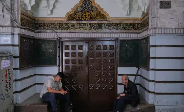 Men sit at the gate of a mosque at Tehran's historic Grand Bazaar, Iran, Monday, June 1, 2026. (AP Photo/Vahid Salemi)