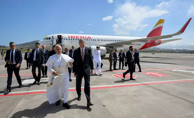 In this handout photo provided by Vatican Media, Pope Leo XIV is accompanied by King Felipe VI of Spain as he deplanes after a technical problem at Tenerife Norte-Los Rodeos International Airport in Tenerife, Spain, Friday, June 12, 2026. (Vatican Media via AP)