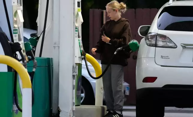 Customer checks gas price before she fills up her vehicle's tank at a gas station in Lincolnshire, Ill., Monday, June 8, 2026. (AP Photo/Nam Y. Huh)