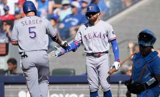 Texas Rangers' Corey Seager (5) celebrates after his solo home run with teammate Brandon Nimmo, second from left, during the sixth inning of a baseball game against the Toronto Blue Jays in Toronto, Saturday, June 27, 2026. (Nathan Denette/The Canadian Press via AP)