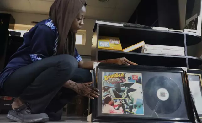 Qawiyat Omizi, a tour guide holds the album cover of Fela Kuti's song Zombie at Kalakuta Museum in Lagos, Nigeria. Saturday, May 30, 2026. (AP Photo/Mansur Ibrahim)