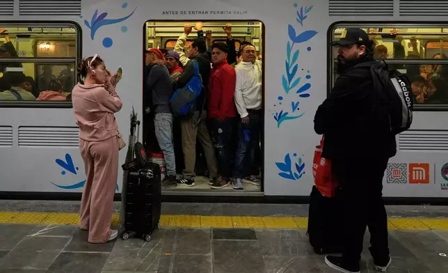 A woman puts on makeup at the subway in Mexico City, Tuesday, June 9, 2026. (AP Photo/Marco Ugarte)