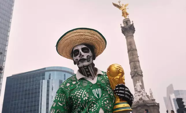 A dancer holds a replica of the World Cup trophy as soccer fans stand along Reforma Avenue in Mexico City, Saturday, June 6, 2026 ahead of the FIFA World Cup. (AP Photo/Moises Castillo)