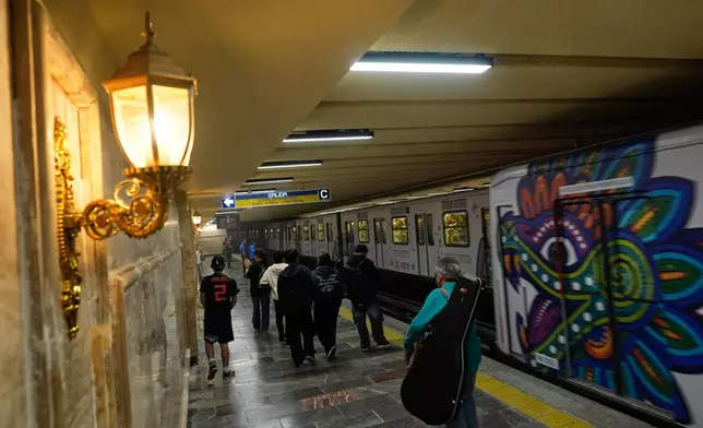 People walk through a subway station that has new lighting, part of preparations for hosting the World Cup soccer tournament in Mexico City, Wednesday, June 10, 2026. (AP Photo/Marco Ugarte)
