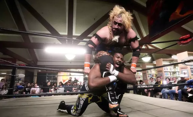 Wrestler Jaguar Montoya, top, applies a hold against OC Hayes during a Lucha Libro pro wrestling event at Benicia Public Library Saturday, May 2, 2026, in Benicia, Calif. (AP Photo/Jeff Chiu)