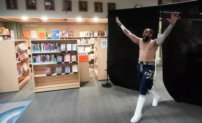 Wrestler TJ Black reacts as he walks past books during a Lucha Libro pro wrestling event at Benicia Public Library Saturday, May 2, 2026, in Benicia, Calif. (AP Photo/Jeff Chiu)