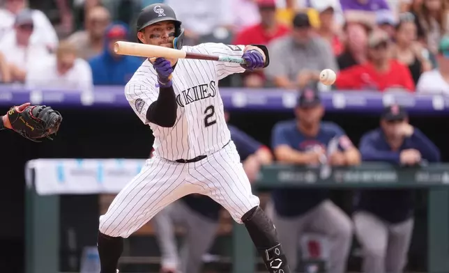 Colorado Rockies' Tyler Freeman puts down a bunt to drive in a run from third base against Boston Red Sox relief pitcher Justin Slaten in the eighth inning of a baseball game Wednesday, June 24, 2026, in Denver. (AP Photo/David Zalubowski)