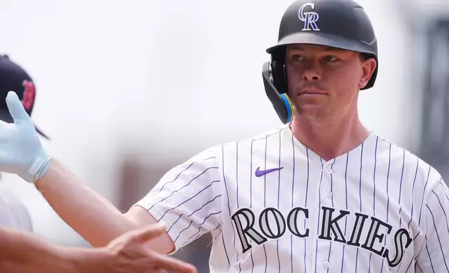 Colorado Rockies pinch-hitter Troy Johnston is congratulated after his RBI single of Boston Red Sox relief pitcher Danny Coulombe in the seventh inning of a baseball game Wednesday, June 24, 2026, in Denver. (AP Photo/David Zalubowski)
