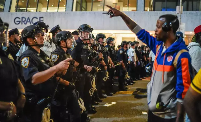 NYPD officers push New York Knicks fans back outside of a watch party in Bryant Park for Game 3 of the NBA Finals basketball series between the Knicks and the San Antonio Spurs, Monday, June 8, 2026, in New York. (AP Photo/Ryan Murphy)