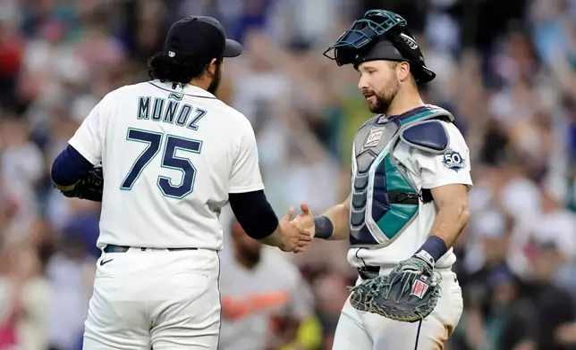 Seattle Mariners pitcher Andrés Muñoz shakes hands with catcher Cal Raleigh after their win over the Baltimore Orioles in a baseball game, Tuesday, June 16, 2026, in Seattle. (AP Photo/John Froschauer)