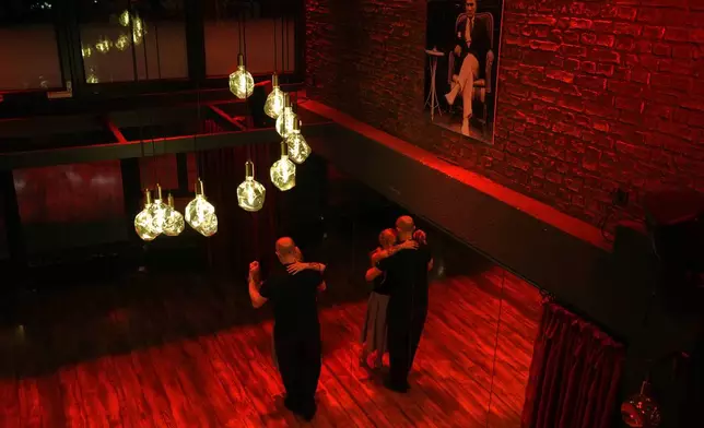 A couple dances tango next to a portrait of modern Turkey founder Mustafa Kemal Ataturk during a milonga evening at La Cumparsita in Istanbul, Turkey, Tuesday, Jan. 27, 2026. (AP Photo/Francisco Seco)