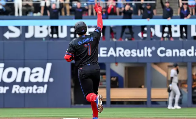Toronto Blue Jays infielder Kazuma Okamoto (7) gestures to the bullpen after hitting a two-run home run scoring Alejandro Kirk, not pictured, against the New York Yankees during first inning of a baseball game in Toronto on Friday, June 12, 2026. (Jon Blacker/The Canadian Press via AP)