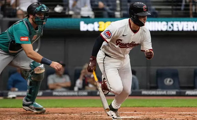 Cleveland Guardians' Cooper Ingle watches his first Major League hit, an RBI single off Seattle Mariners starting pitcher Logan Gilbert as Cal Raleigh moves into position during the third inning of a baseball game, Saturday, June 27, 2026, in Cleveland. (AP Photo/Phil Long)