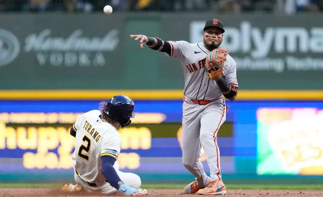 San Francisco Giants' Luis Arraez, right, throws to first base to turn a double play after tagging out Milwaukee Brewers' Brice Turang (2) at second during the fourth inning of a baseball game Monday, June 1, 2026, in Milwaukee. (AP Photo/Aaron Gash)