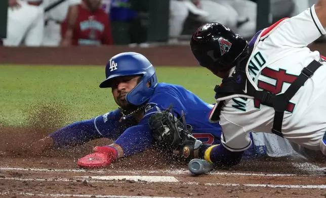 Arizona Diamondbacks catcher Gabriel Moreno (14) tags out Los Angeles Dodgers' Mookie Betts, left, who was trying to steal home on a ball hit by Max Muncy in the first inning of a baseball game, Monday, June 1, 2026, in Phoenix. (AP Photo/Rick Scuteri)
