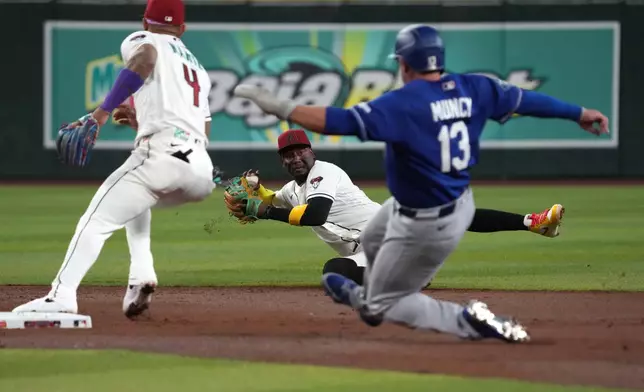 Arizona Diamondbacks shortstop Geraldo Perdomo, center, tries to make a play from the ground against the Los Angeles Dodgers in the second inning of a baseball game, Monday, June 1, 2026, in Phoenix. (AP Photo/Rick Scuteri)