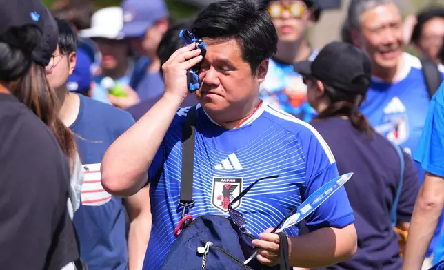 FILE - A Japan soccer fan wipes his brow while standing in the heat in downtown Dallas, June 24, 2026. (AP Photo/LM Otero, File)