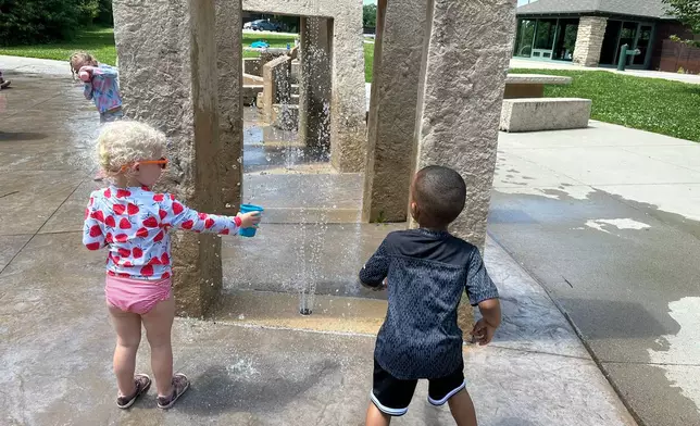 Children play at a water sprayground in Des Moines, Iowa, Monday, June 29, 2026. (AP Photo/Hannah Fingerhut)
