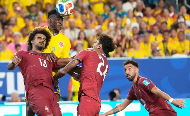 Colombia's Jhon Lucumi (3) leaps above Portugal's Renato Veiga (13) and Samu Costa (24) to head the ball during the World Cup Group K soccer match between Colombia and Portugal in Miami Gardens, Fla., Saturday, June 27, 2026. (AP Photo/Rebecca Blackwell)