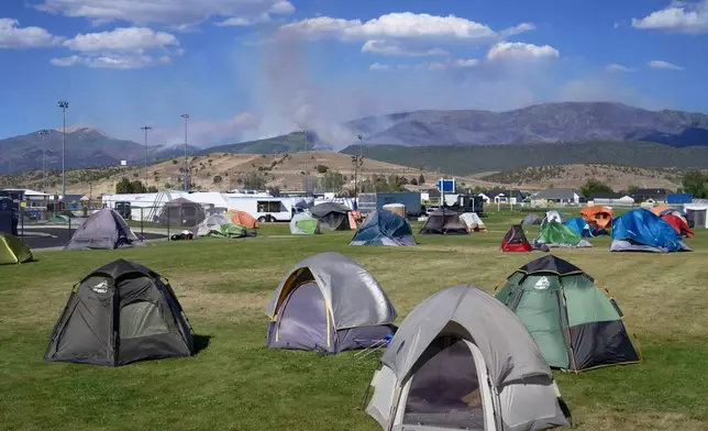 Firefighter tents sit across an elementary school lawn with the Cottonwood Fire in the background, in Beaver, Utah on Saturday, June 27, 2026. (AP Photo/Ty ONeil)