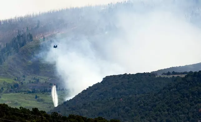 A helicopter drops water on the Cottonwood Fire burning near Beaver, Utah, on Saturday, June 27, 2026. (AP Photo/Noah Berger)