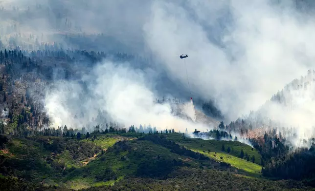 A helicopter drops water on the Cottonwood Fire burning near Beaver, Utah, on Saturday, June 27, 2026. (AP Photo/Noah Berger)