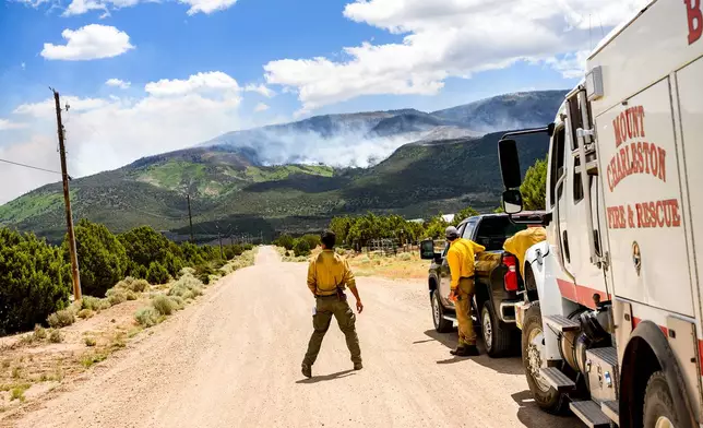 A firefighter watches as the Cottonwood Fire burns near Beaver, Utah, on Saturday, June 27, 2026. (AP Photo/Noah Berger)