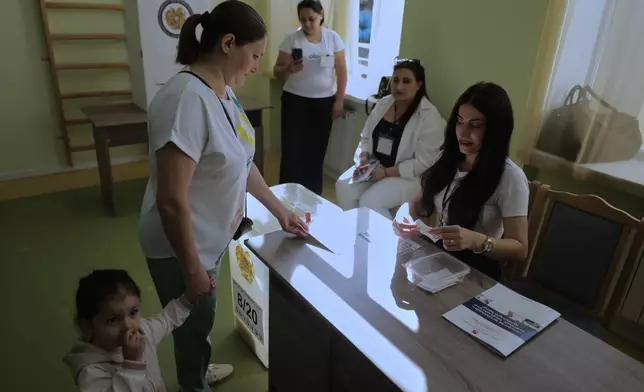 A woman gets a ballot at a polling station during the parliamentary election in Yerevan, Armenia, Sunday, June 7, 2026. (AP Photo/Anthony Pizzoferrato)