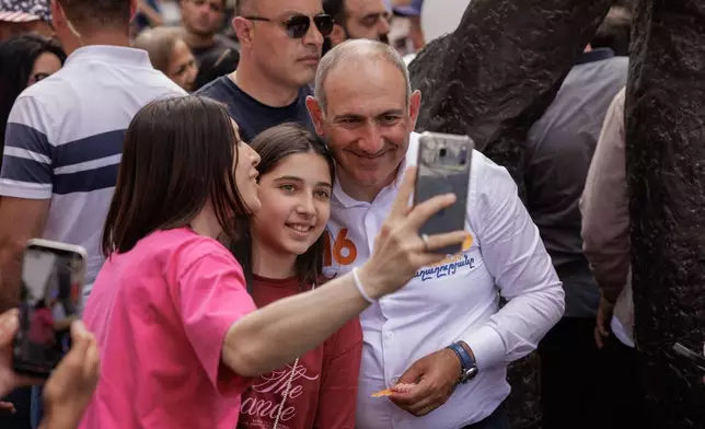 Armenian Prime Minister Nikol Pashinyan poses for a selfie photo with a supporter as he walks on Northern Avenue in Yerevan, Armenia, Monday, June 1, 2026, during public celebrations marking International Children's Day. (AP Photo/Anthony Pizzoferrato)