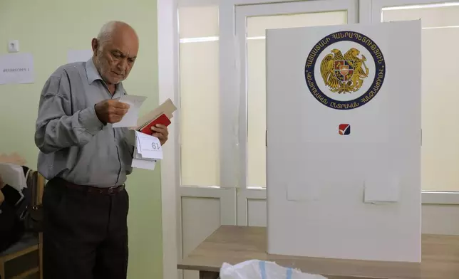 A man looks at his ballot at a polling station during the parliamentary election in Yerevan, Armenia, Sunday, June 7, 2026. (AP Photo/Anthony Pizzoferrato)