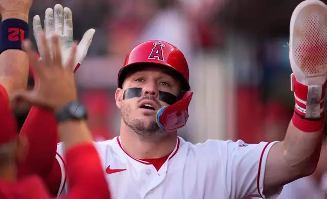 Los Angeles Angels' Mike Trout is congratulated by teammates in the dugout after scoring on a wild pitch during the second inning of a baseball game against the Colorado Rockies, Wednesday, June 3, 2026, in Anaheim, Calif. (AP Photo/Mark J. Terrill)