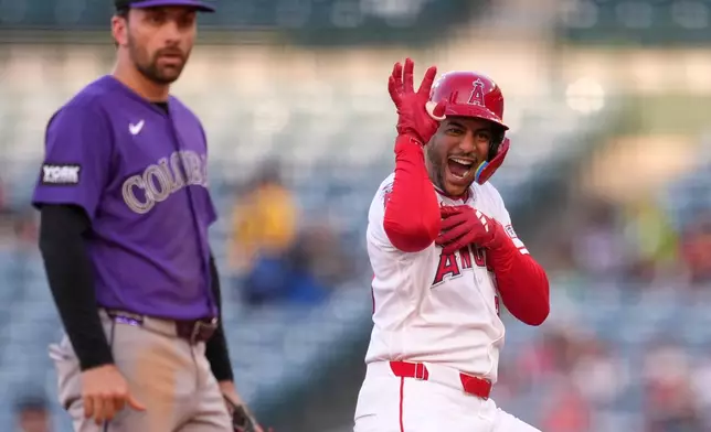 Los Angeles Angels' Jose Siri, right, gestures toward his dugout after hitting an RBI double as Colorado Rockies second baseman Edouard Julien looks on during the second inning of a baseball game Wednesday, June 3, 2026, in Anaheim, Calif. (AP Photo/Mark J. Terrill)