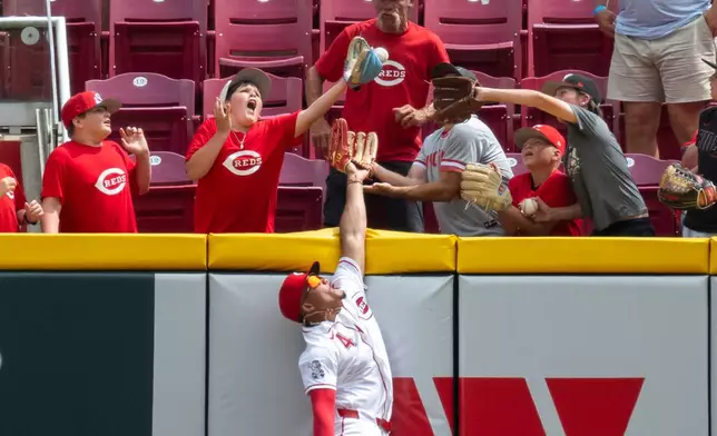 Cincinnati Reds' right fielder Noelvi Marte, bottom, misses a home run hit by Arizona Diamondbacks' Gabriel Moreno in the eight inning of a baseball game, Sunday, June 14, 2026, in Cincinnati. (AP Photo/Michael Swensen)