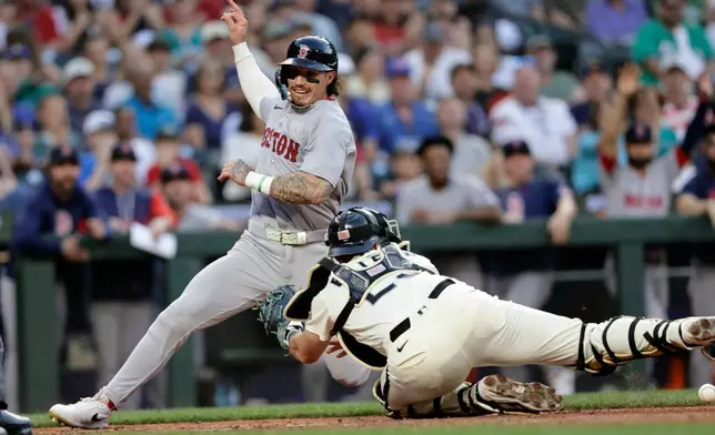 Boston Red Sox's Jarren Duran scores with Seattle Mariners catcher Cal Raleigh reaching with an empty glove during the seventh inning of a baseball game, Friday, June 19, 2026, in Seattle. (AP Photo/John Froschauer)