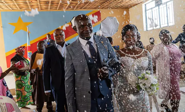 A newly married couple walks down the aisle at their wedding as guests shower them with confetti amid an Ebola outbreak in Ituri Province in Bunia, Congo, Saturday, June 6, 2026. (AP Photo/Moses Sawasawa)